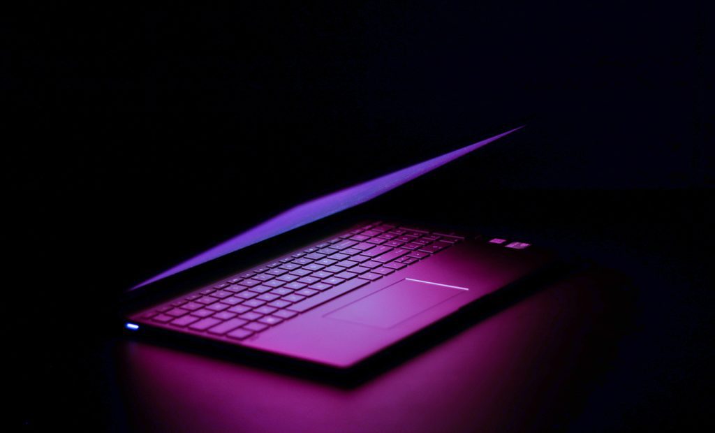 A laptop on a desk in dark background used for virtual geology fieldwork and remote collaboration for photogrammetric digital outcrop models